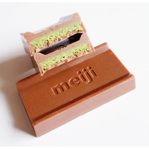 A cross-section of a Meiji Matcha Chocolate piece, showing the vibrant green tea filling surrounded by a layer of milk chocolate.
