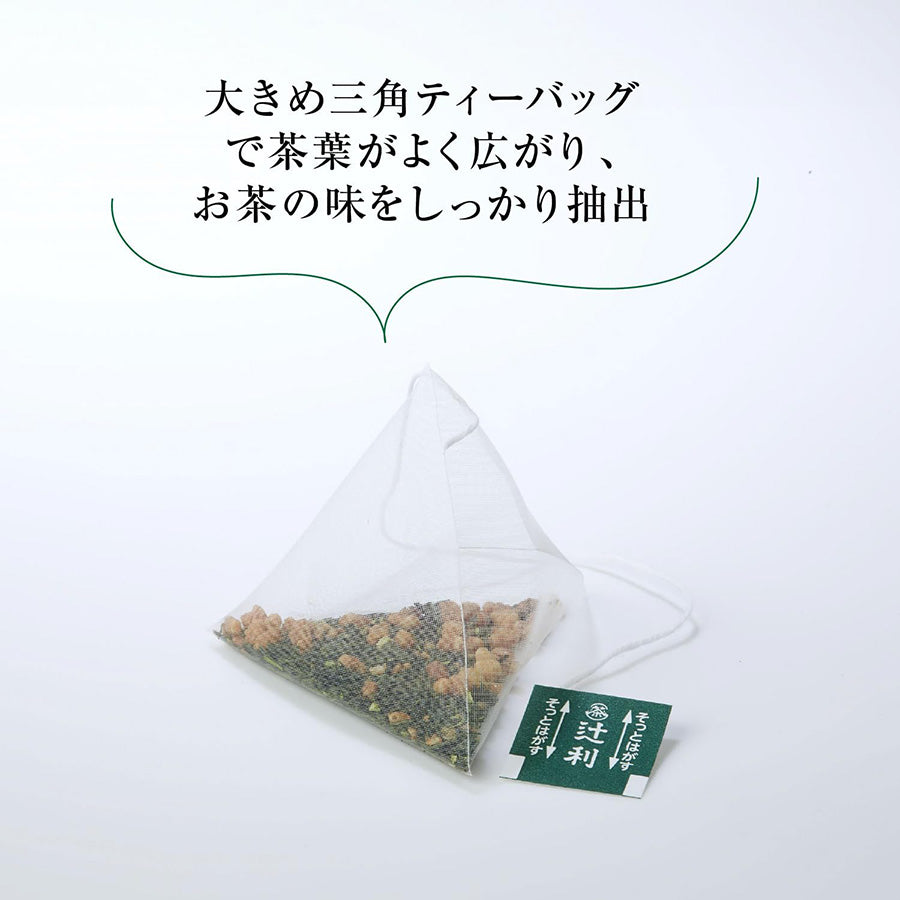 A close-up of a single Tsujiri triangular Genmaicha tea bag, showing the mixture of green tea leaves and brown rice kernels.
